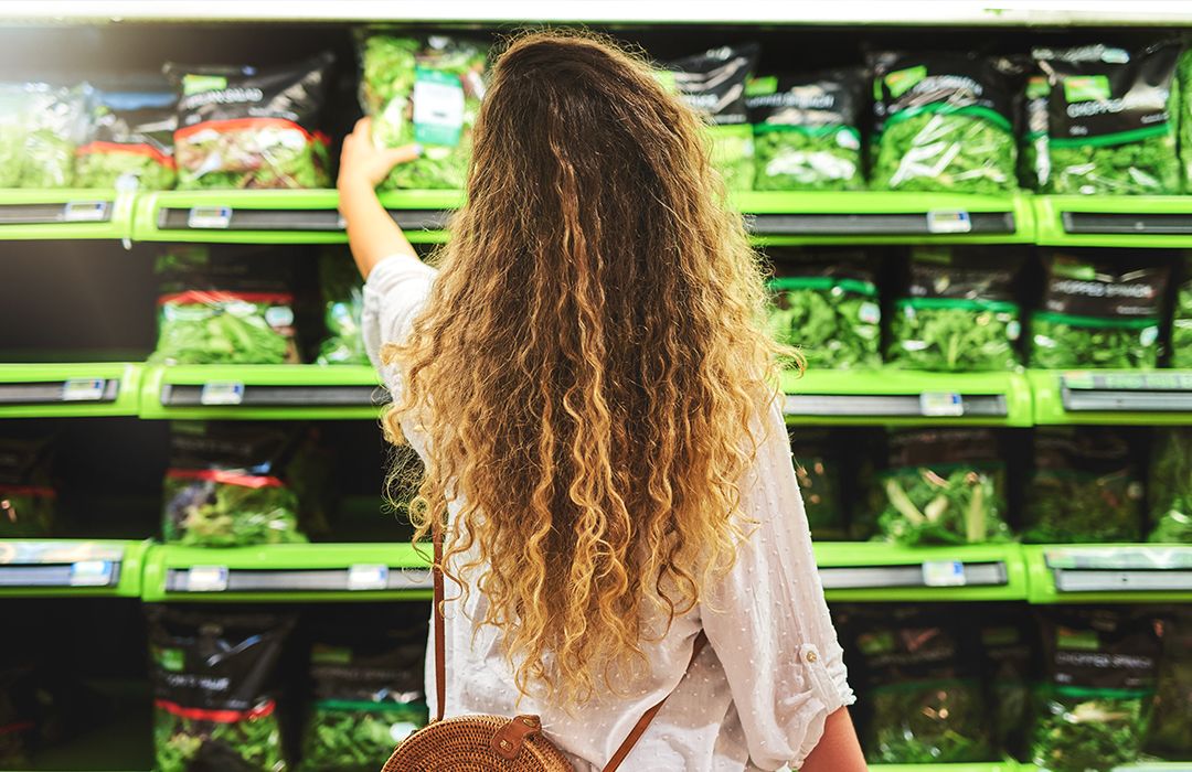 woman shopping for salad at the grocery store in pfa free packaging