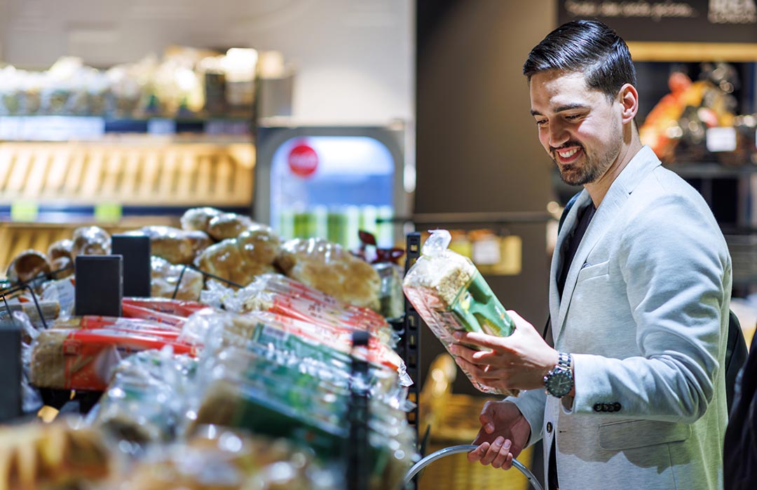 man shopping for bread in recyclable packaging in the grocery store